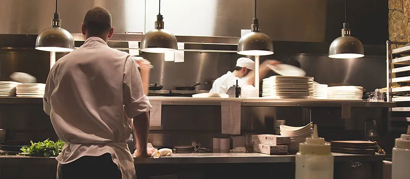 Chef and staff working in busy restaurant kitchen