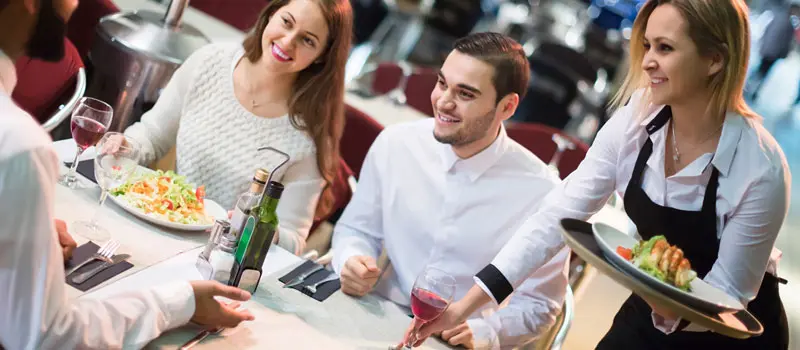 Waitress serving customers at busy UK restaurant